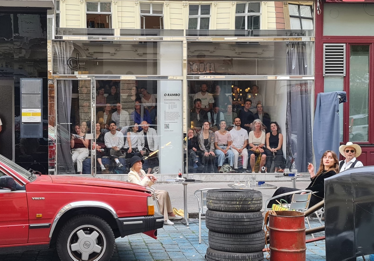 The audience behind the gallery window at O Rambo